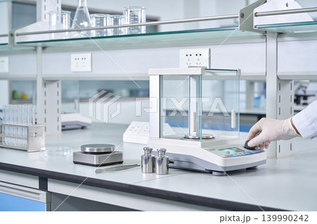 Scientist using precision laboratory scale for accurate measurements in a modern lab Scientist using precision laboratory scale for accurate measurements in a modern lab 139990242
