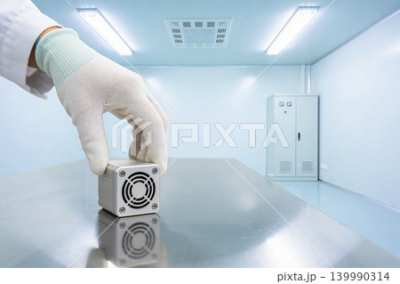 Scientist in cleanroom places small electronic device on sterile metal table Scientist in cleanroom places small electronic device on sterile metal table 139990314