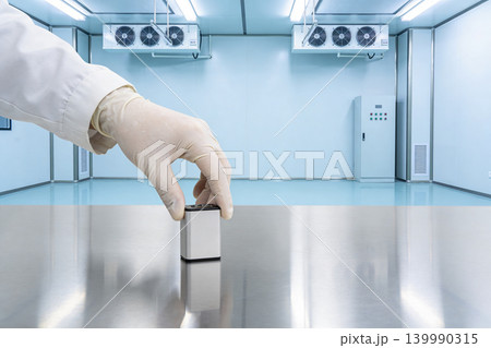 Scientist in sterile lab places small device on reflective metal surface Scientist in sterile lab places small device on reflective metal surface 139990315