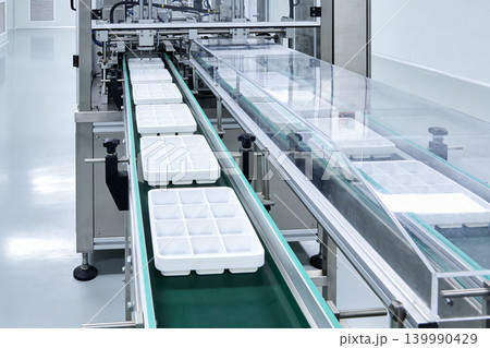 Automated production line with white trays moving on a conveyor belt Automated production line with white trays moving on a conveyor belt 139990429