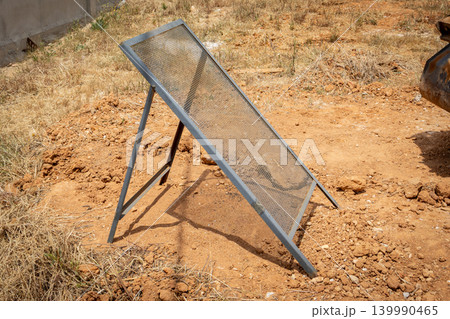 Metal sieve for separating soil and gravel on a construction site Metal sieve for separating soil and gravel on a construction site 139990465