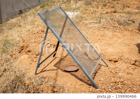 Outdoor sieve for soil analysis on a dry, dusty ground with sparse vegetation 139990466