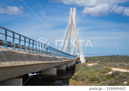 Modern cable-stayed bridge with striking white towers against a blue sky Arade river Portugal Portimao Modern cable-stayed bridge with striking white towers against a blue sky Arade river Portugal Portimao 139990482