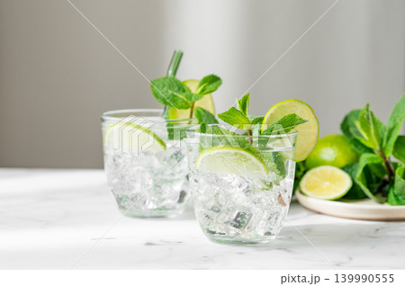 A fresh mojito with lime, mint and ice in glasses. Citrus lemonade or cocktail on a marble table 139990555
