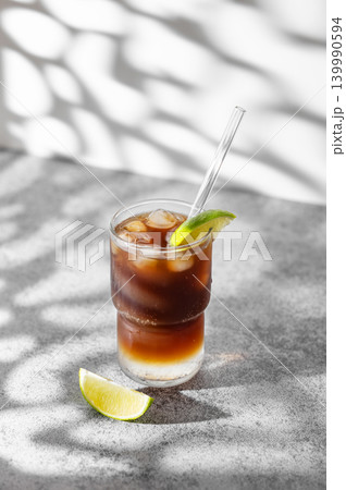 Cold Coffee Tonic Drink With Lime and Ice on light background with shadows Cold Coffee Tonic Drink With Lime and Ice on light background with shadows 139990594