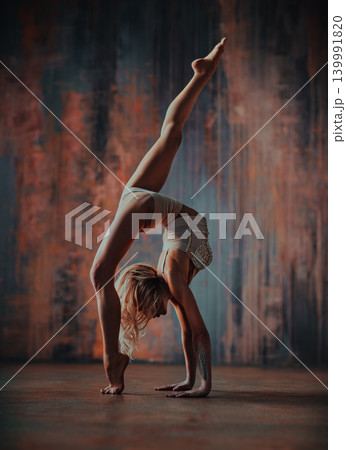 Young woman gymnast stretching on rusty wall background Young woman gymnast stretching on rusty wall background 139991820