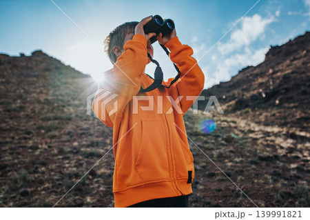 Portrait of boy tourist looking in binoculars in mountains 139991821