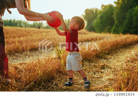 Young mother gives the ball to her two-year-old son in a field 139991914