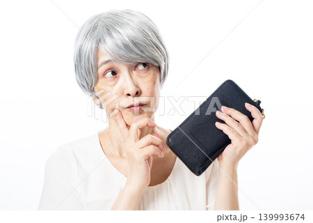 黒い長財布を片手に考える白髪のシニア女性 黒い長財布を片手に考える白髪のシニア女性 139993674
