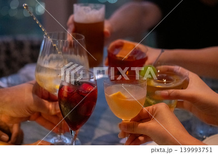 A group of people raise a toast with glasses of cocktail on the table A group of people raise a toast with glasses of cocktail on the table 139993751