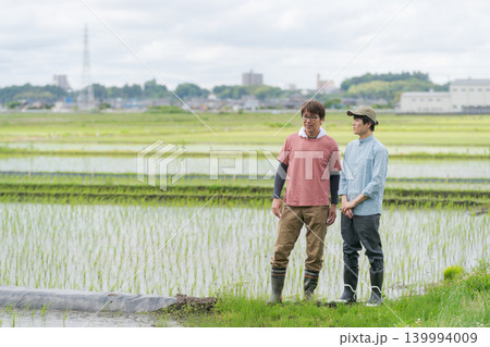 田んぼの畦道に立つ2人の農家 田んぼの畦道に立つ2人の農家 139994009