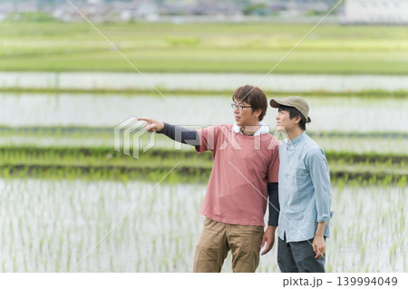 田んぼの畦道に立つ2人の農家 139994049