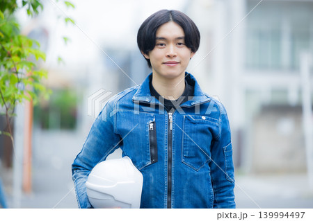 スマホを操作する若い作業員 スマホを操作する若い作業員 139994497