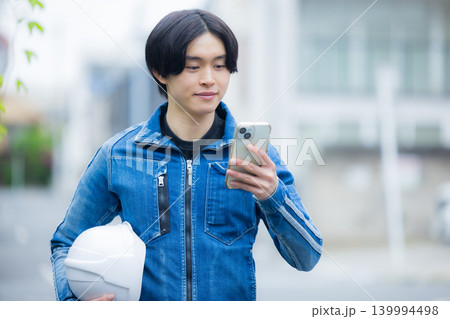 スマホを操作する若い作業員　 139994498