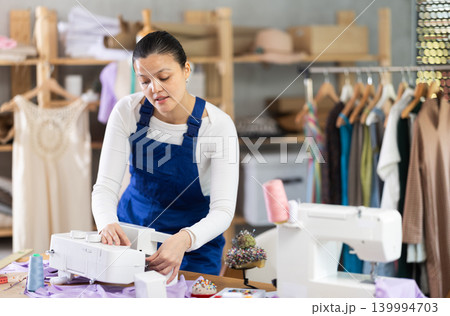Skilled young repairwoman repairing sewing-machine 139994703
