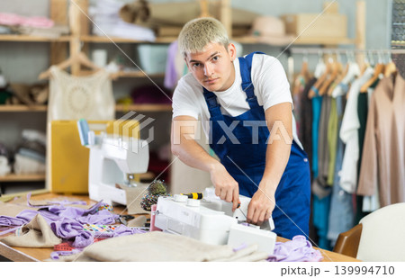 Skilled young repairman repairing sewing-machine 139994710