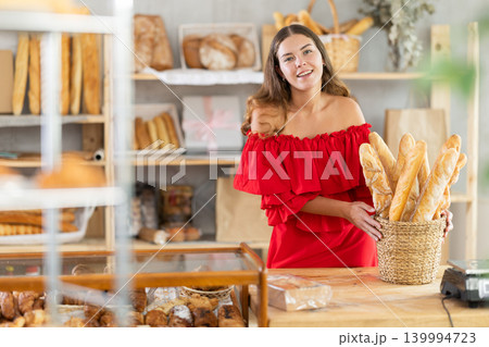 Young woman in red dress leaning on bakery counter Young woman in red dress leaning on bakery counter 139994723