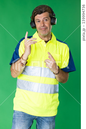 Adult man in reflective polo shirt listening to music and dancing on green screen 139994736