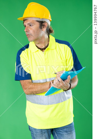 Adult man in reflective polo shirt and hard hat holding inventory documents on green screen Adult man in reflective polo shirt and hard hat holding inventory documents on green screen 139994767