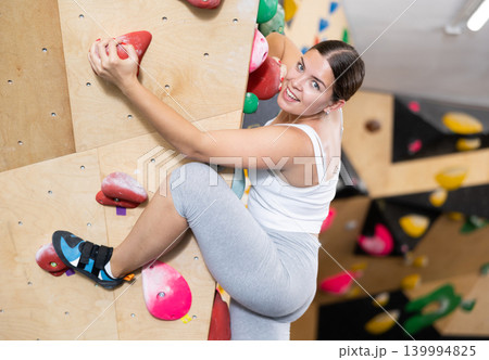 Woman training at bouldering gym without special climbing equipment 139994825