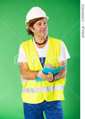 Man in reflective vest and hard hat on green screen background with paper inventory form 139994832