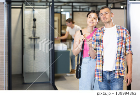 Interested couple discussing choice of bathroom fixtures in plumbing store 139994862