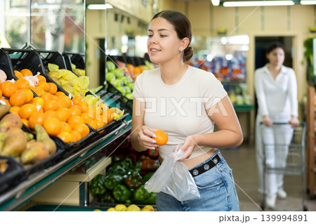 Young woman in supermarket chooses quality juicy ripe tangerines Young woman in supermarket chooses quality juicy ripe tangerines 139994891
