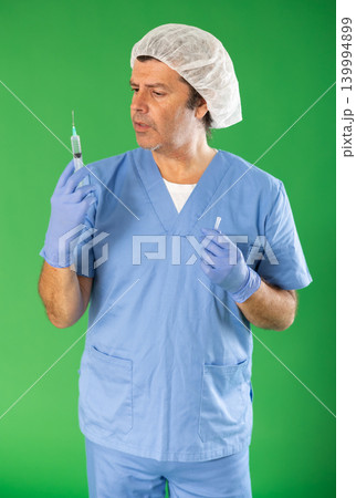 Adult male medic explaining injection procedure with syringe on green screen Adult male medic explaining injection procedure with syringe on green screen 139994899
