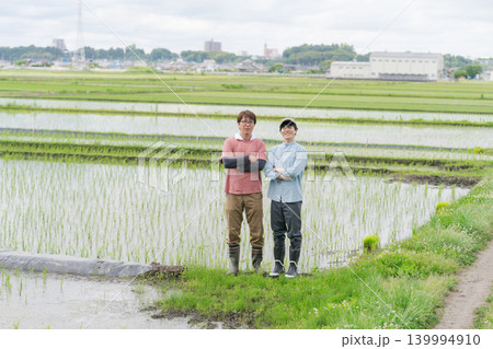 田んぼの畦道に立つ2人の農家 田んぼの畦道に立つ2人の農家 139994910