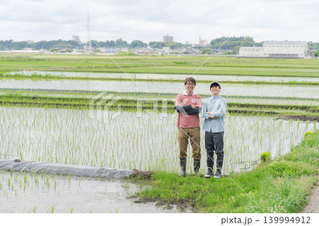 田んぼの畦道に立つ2人の農家 139994912