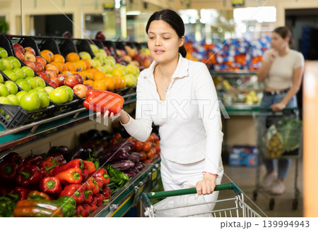 Asian woman in greengrocer s shop,picking bell pepper in small package Asian woman in greengrocer s shop,picking bell pepper in small package 139994943
