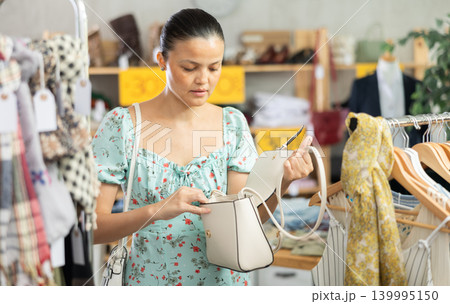 Selective young Asian woman choosing handbag in clothing store 139995150