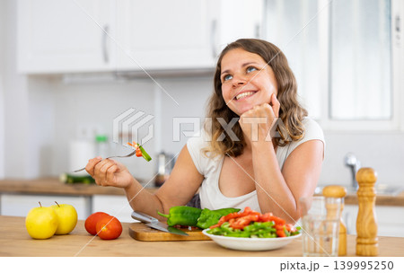 Portrait of positive woman eating salad at home Portrait of positive woman eating salad at home 139995250