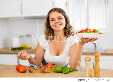 Portrait of woman cooking and eating salad at home 139995258