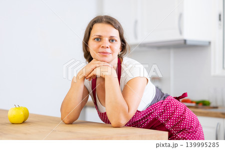 Portrait of woman in apron posing near table Portrait of woman in apron posing near table 139995285