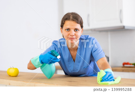 Workwoman of cleaning service wiping table in kitchen Workwoman of cleaning service wiping table in kitchen 139995288