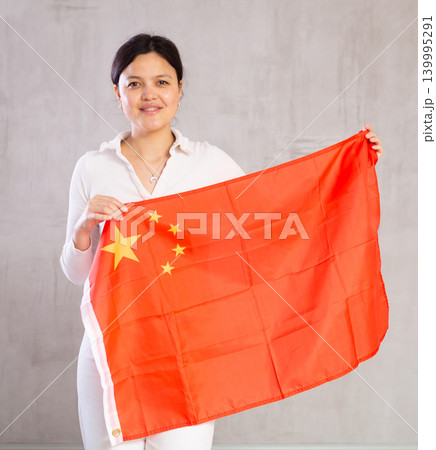 Joyful female fan of the favorite team of China with national flag in her hands Joyful female fan of the favorite team of China with national flag in her hands 139995291