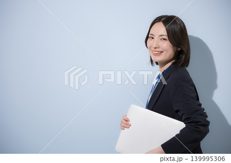 水色背景で名札をつけたノートパソコンを持つ働くかわいい女性社員のビジネスとITなどのイメージ 水色背景で名札をつけたノートパソコンを持つ働くかわいい女性社員のビジネスとITなどのイメージ 139995306