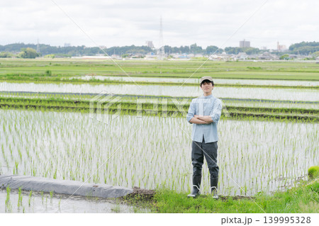 田んぼの畦道に立つ若い農家 139995328