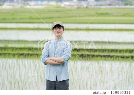 田んぼの畦道に立つ若い農家 139995331