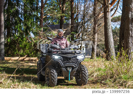 Woman riding an ATV in an Estonian forest for outdoor adventure and woodland exploration 139997256