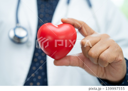 Doctor holding a red heart in hospital ward, healthy strong medical. 139997555