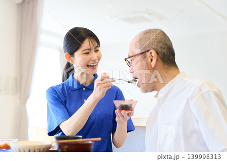 シニアの食事介助をするアジア人介護士 シニアの食事介助をするアジア人介護士 139998313
