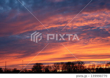 Spectacular sunset sky with vibrant orange and purple clouds over trees Spectacular sunset sky with vibrant orange and purple clouds over trees 139998770