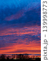 Vibrant dramatic sunset sky with colorful clouds above dark forest 139998773