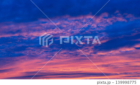 Dramatic colorful sunset clouds glowing across deep blue evening sky 139998775