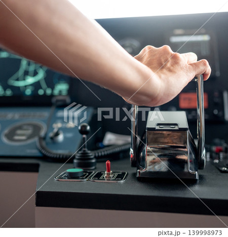 Captain hand holding throttle control on boat dashboard 139998973