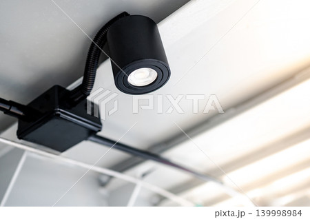 Modern black cylinder LED spotlight or cylindrical downlight hanging on the ceiling 139998984