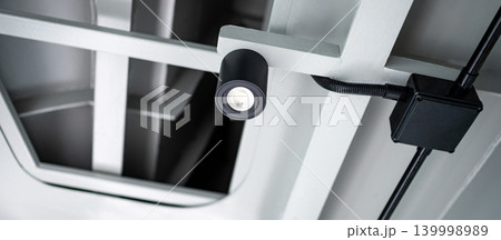 Modern black cylinder LED spotlight or cylindrical downlight hanging on the ceiling 139998989