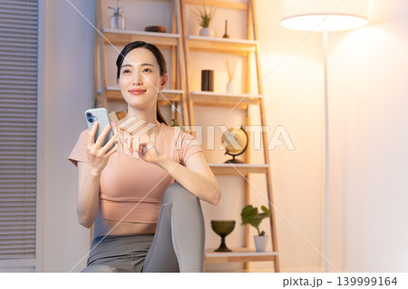 夜スマホを見るヨガウェアの女性 139999164